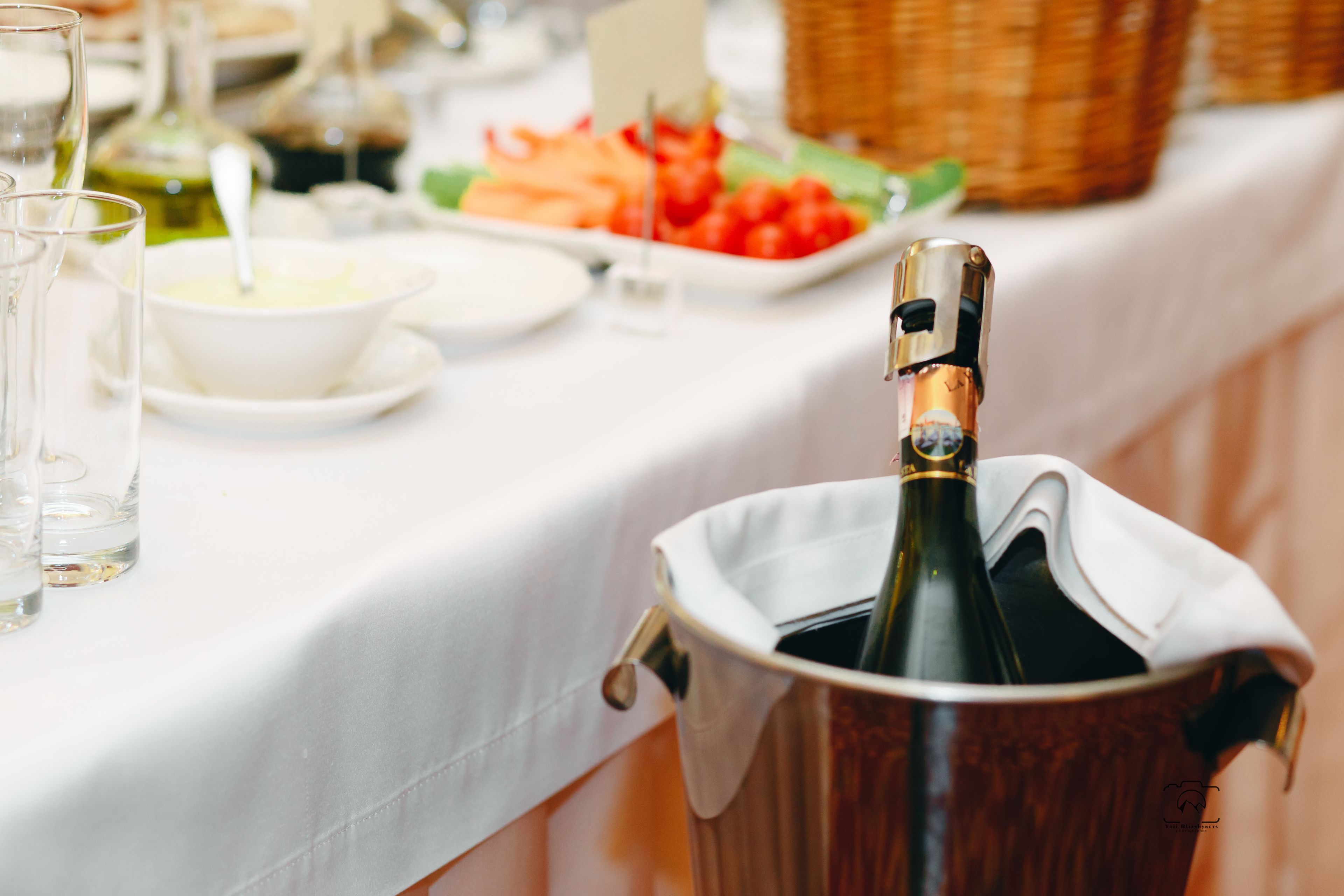 Une table avec une bouteille de champagne dans un seau à glace, entourée de différents plats et de verres.