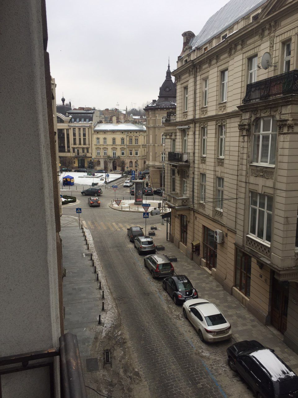 Vista de la calle con coches aparcados, edificios y cielo despejado.