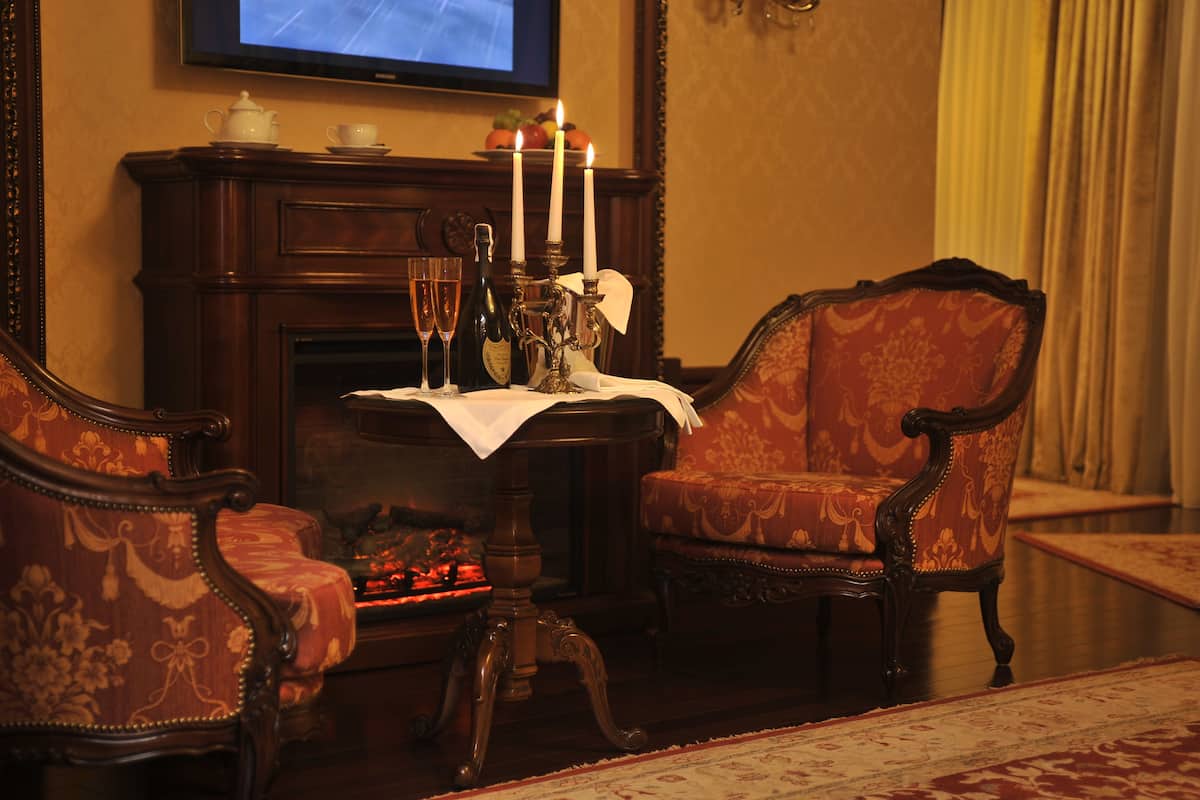 A room with a fireplace, a table with candles, a television, and ornate furniture.