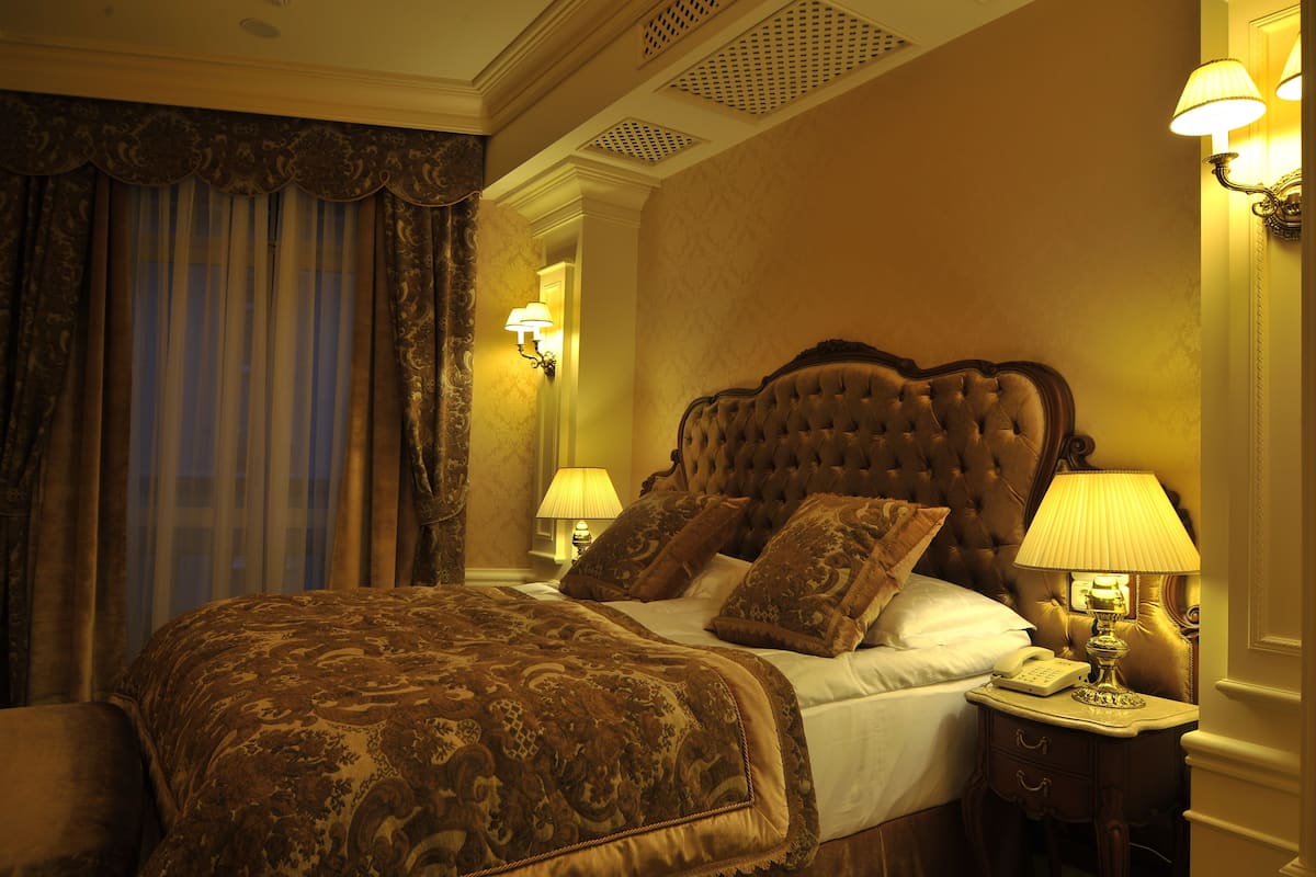 A well-appointed bedroom with a large bed, ornate headboard, and two bedside lamps.