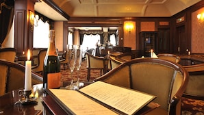 A formal dining room with a menu, a bottle of Veuve Clicquot, and candles on a table.
