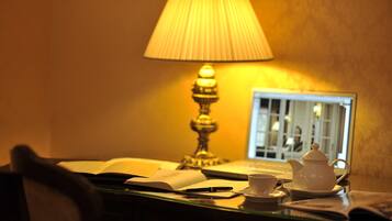 A desk with a laptop, a teapot, a cup, and an open book.