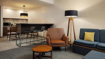Una sala moderna con un sofá, un sillón, una mesa de centro y un comedor con sillas y una mesa.