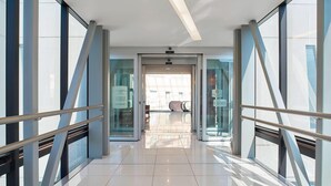 A modern hotel corridor with glass doors, metal railings, and a tiled floor. - Courtyard Mexico City Airport (Mexico City)