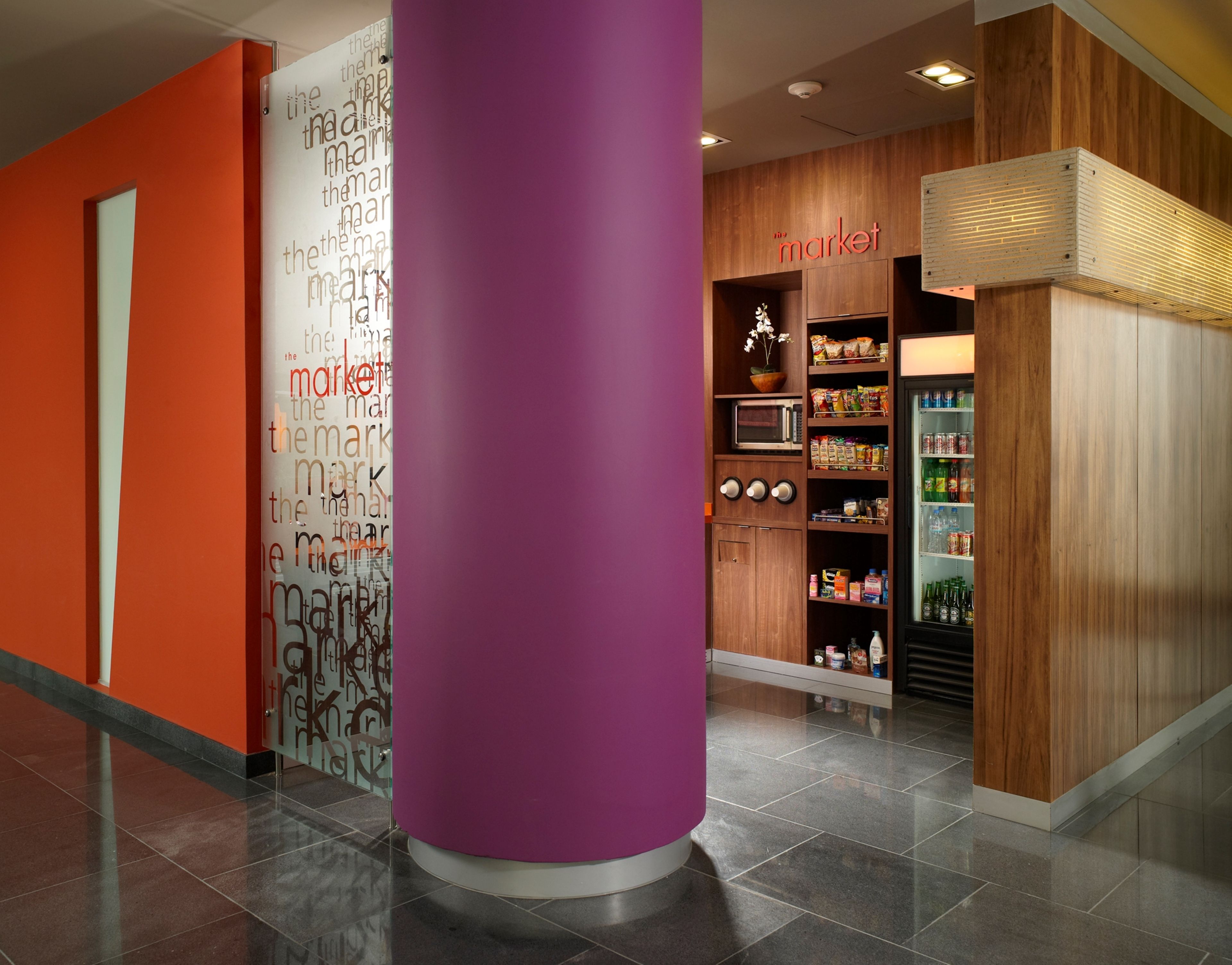A modern interior with a purple pillar, a 'The Market' food section, and a microwave.