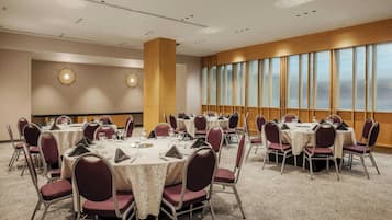 A conference room with round tables, chairs, and a large window with blinds.