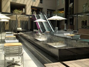 Un área de estar moderna al aire libre con fuente de agua, que incluye una fuente y disposiciones para sentarse.