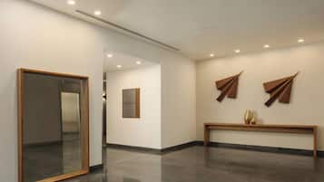 Um corredor com espelho, um banco e arte abstrata nas paredes.