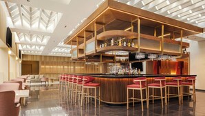 A modern bar area with a curved counter, multiple seating options, and a high ceiling with geometric lighting. - Courtyard Mexico City Airport (Mexico City)
