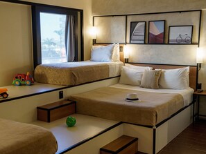 A hotel room with two beds, a window with curtains, a lamp, framed pictures on the wall, and a toy car on the windowsill. - ibis Sao Luis (São Luís)