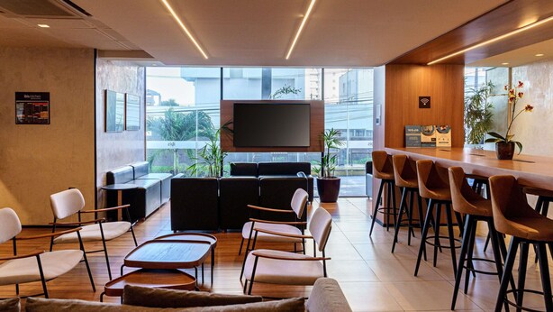 Een modern interieur met een lange tafel en stoelen, een bank en een flatscreen televisie aan de muur.