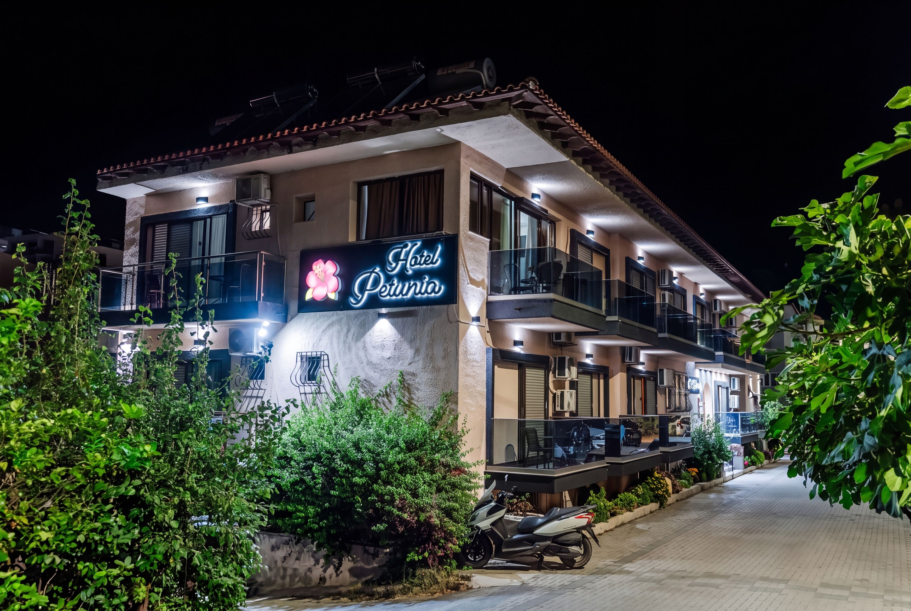 A hotel named 'Hotel Petunia' with a balcony, outdoor seating, and a motorcycle parked in front.