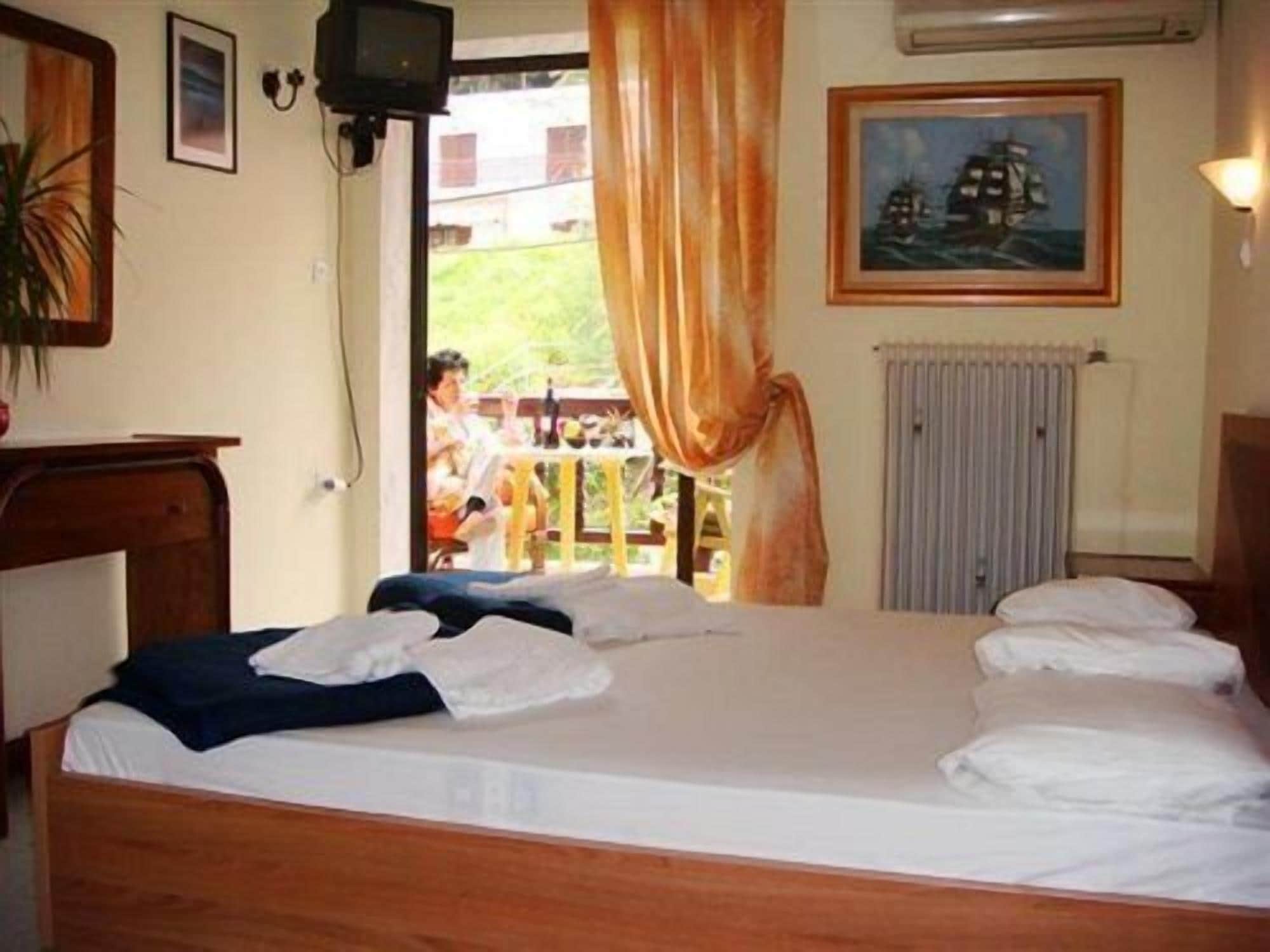 Una habitación con una cama, televisión, un cuadro y una ventana con cortinas.