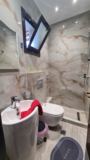 A modern bathroom with a marble backsplash, a built-in TV, a shower, and a bidet. - Hotel Petunia (Sithonia)