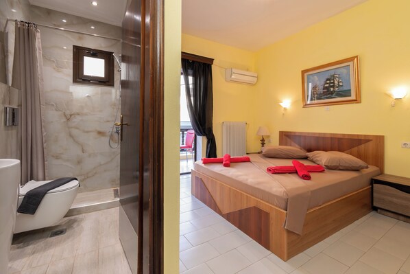 A modern bathroom with a shower, toilet, and a marble wall. - Hotel Petunia (Sithonia)