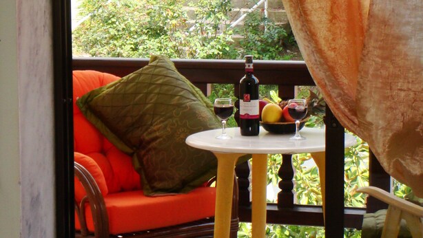 A room with a wooden chair and a small table with a bottle of wine and a glass. - Hotel Petunia (Sithonia)