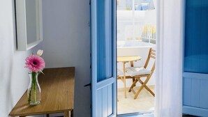 Puerta abierta que da a un balcón con mesa y sillas.