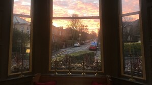 A room with a large bay window overlooking a street during sunset. - Martin's Guesthouse (Edinburgh)
