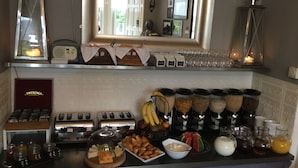 A breakfast buffet with various food items, a toaster, and a mirror above the counter. - Martin's Guesthouse (Edinburgh)