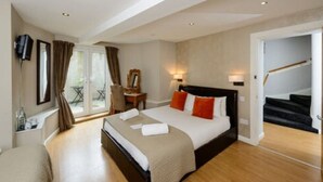 A hotel room with a large bed, a desk with a chair, a TV mounted on the wall, and a staircase leading to an upper floor. - Martin's Guesthouse (Edinburgh)