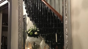 A mirror with an ornate silver frame reflecting a staircase with black balusters and a wooden handrail. - Martin's Guesthouse (Edinburgh)