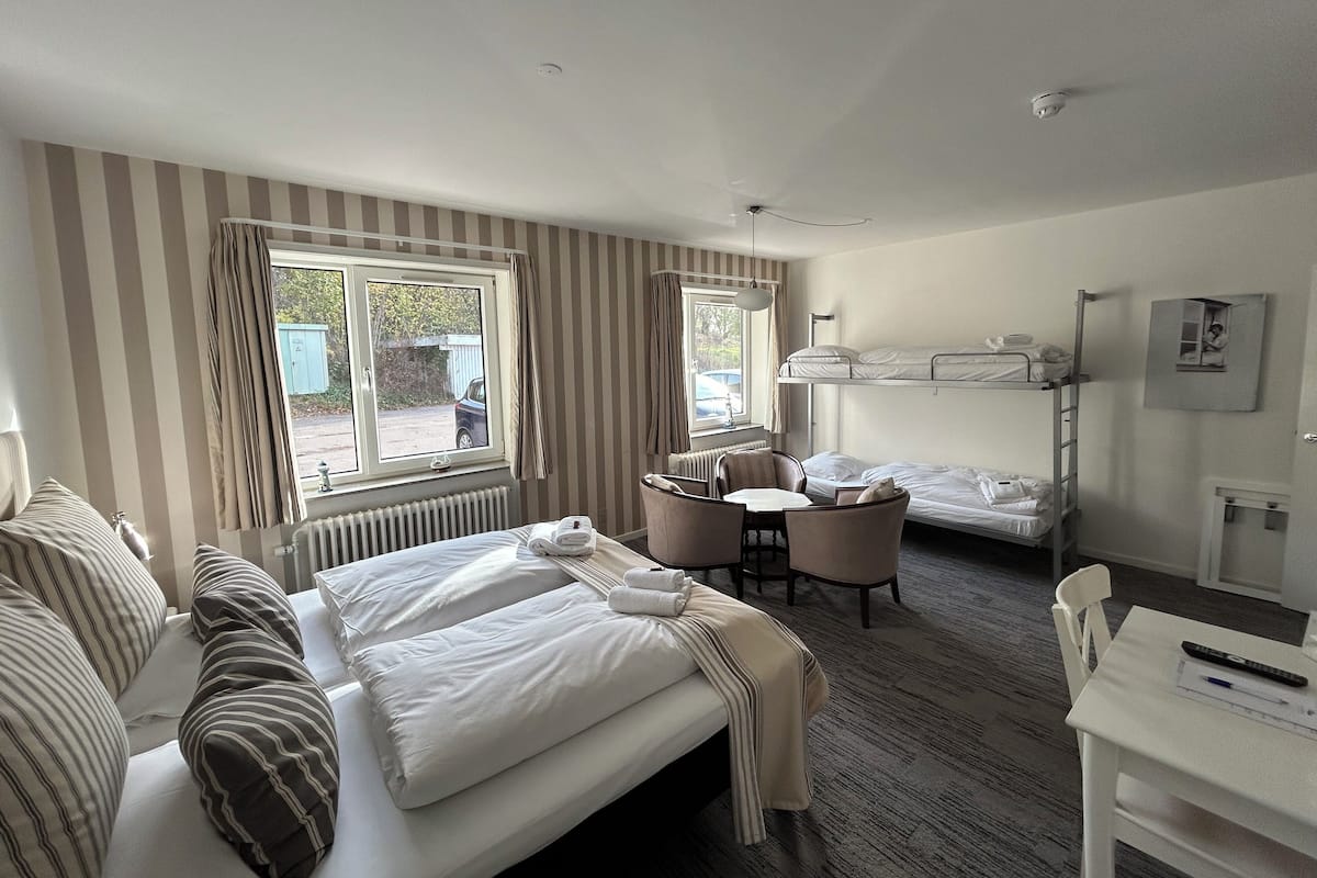 Una habitación de hotel con una cama, un escritorio, una silla y una litera.
