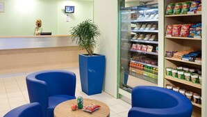 Ein Empfangsbereich mit Theke, Zimmerpflanze und einer mit Snacks gefüllten Kühlschrank.
