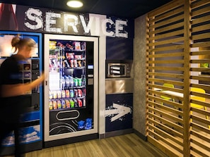 Ein Automate mit der Aufschrift 'SERVICE', ausgestattet mit einem digitalen Display, einer Mikrowelle und einem kleinen Kühlschrank.