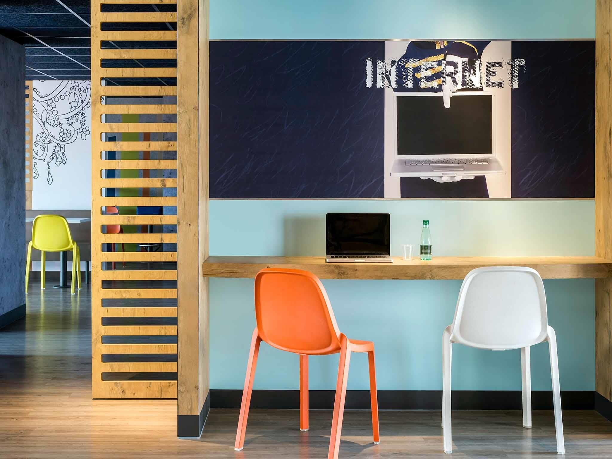 Ein Arbeitsplatz mit zwei Stühlen, einem Laptop und einer Wand mit dem Wort 'INTERNET' in stilvoller Schrift.