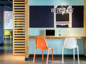 Een werkplek met twee stoelen, een laptop en een muur waarop 'INTERNET' in opvallende letters staat.
