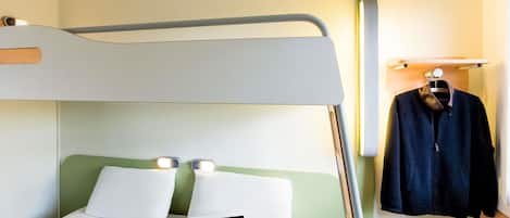 A bunk bed with a laptop on the lower bunk, a hanging garment, and a shelf with a light fixture.