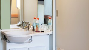 Een badkamer met een witte wastafel, een spiegel en een handdoekhouder.