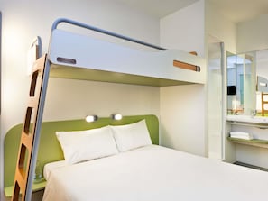 A bunk bed with a ladder, a bedside table, a mirror, and a small shelf with towels.
