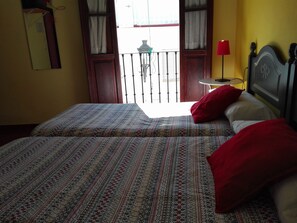 A room with two beds, a balcony with a view, a red lamp, and a small table. - Hostal La Posada del Recovero (Genalguacil)