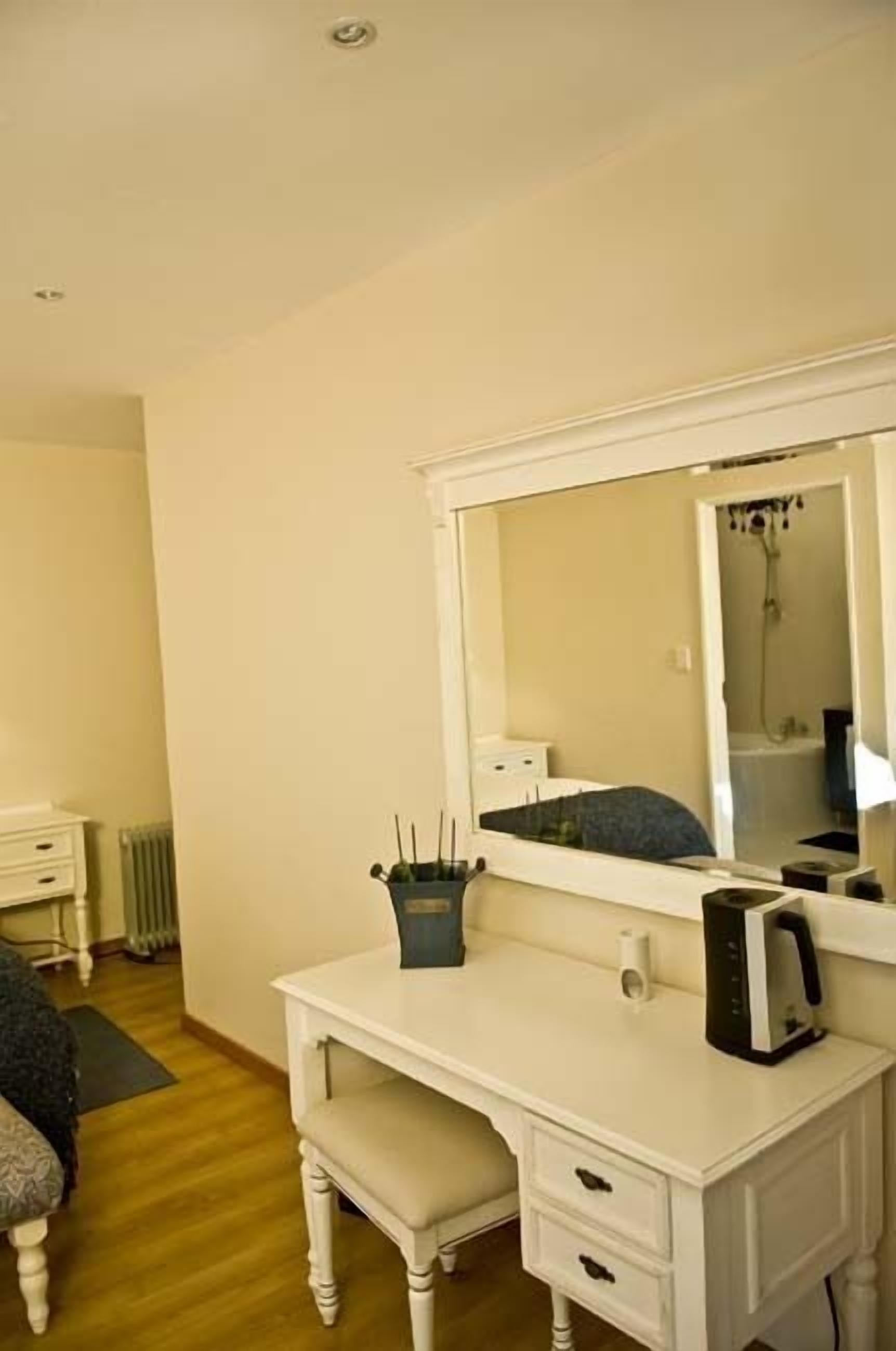 A white vanity with a mirror, a small table, and a bench.