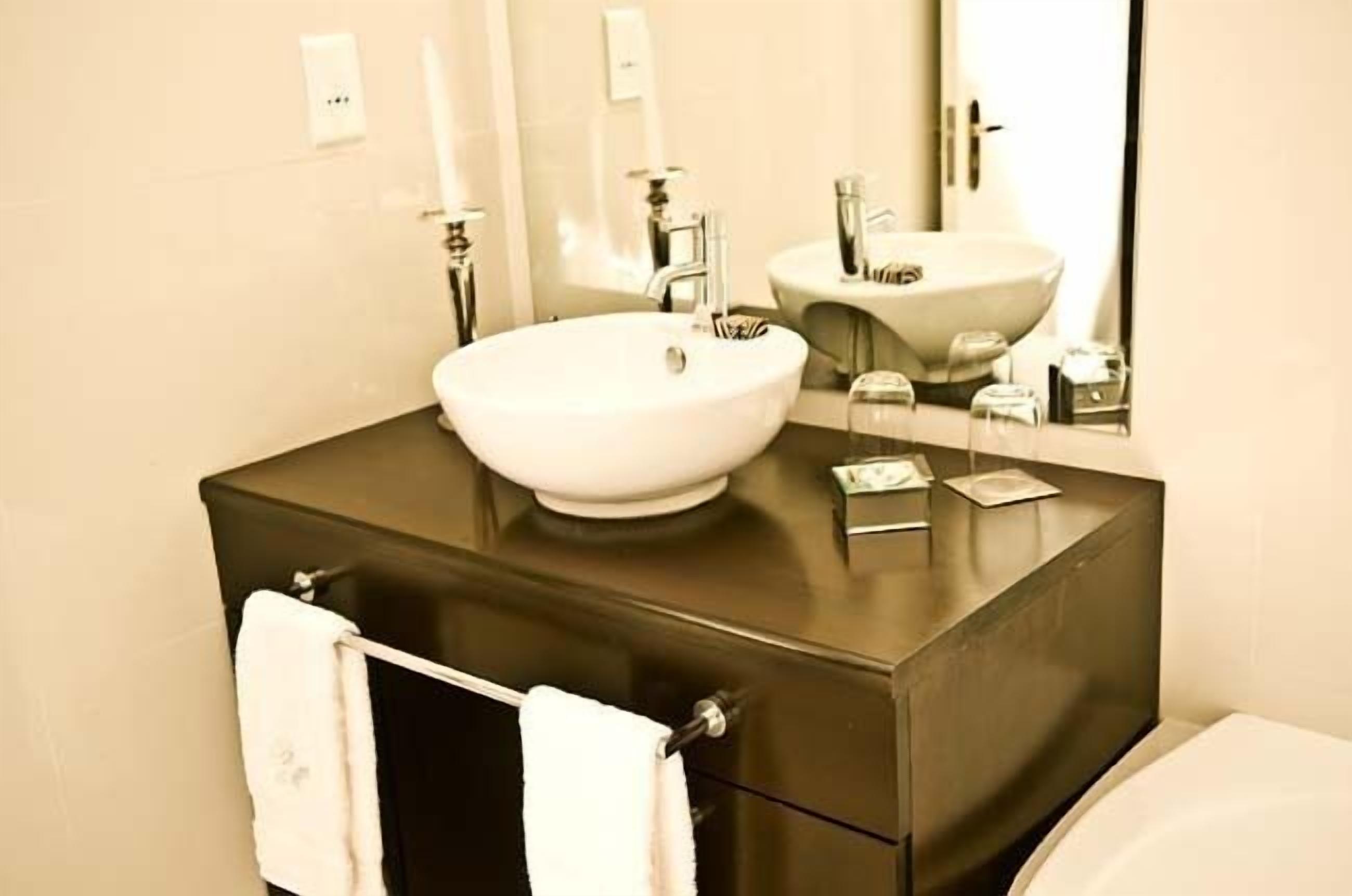 A bathroom with a large white sink, a dark countertop, and a mirror above the sink.