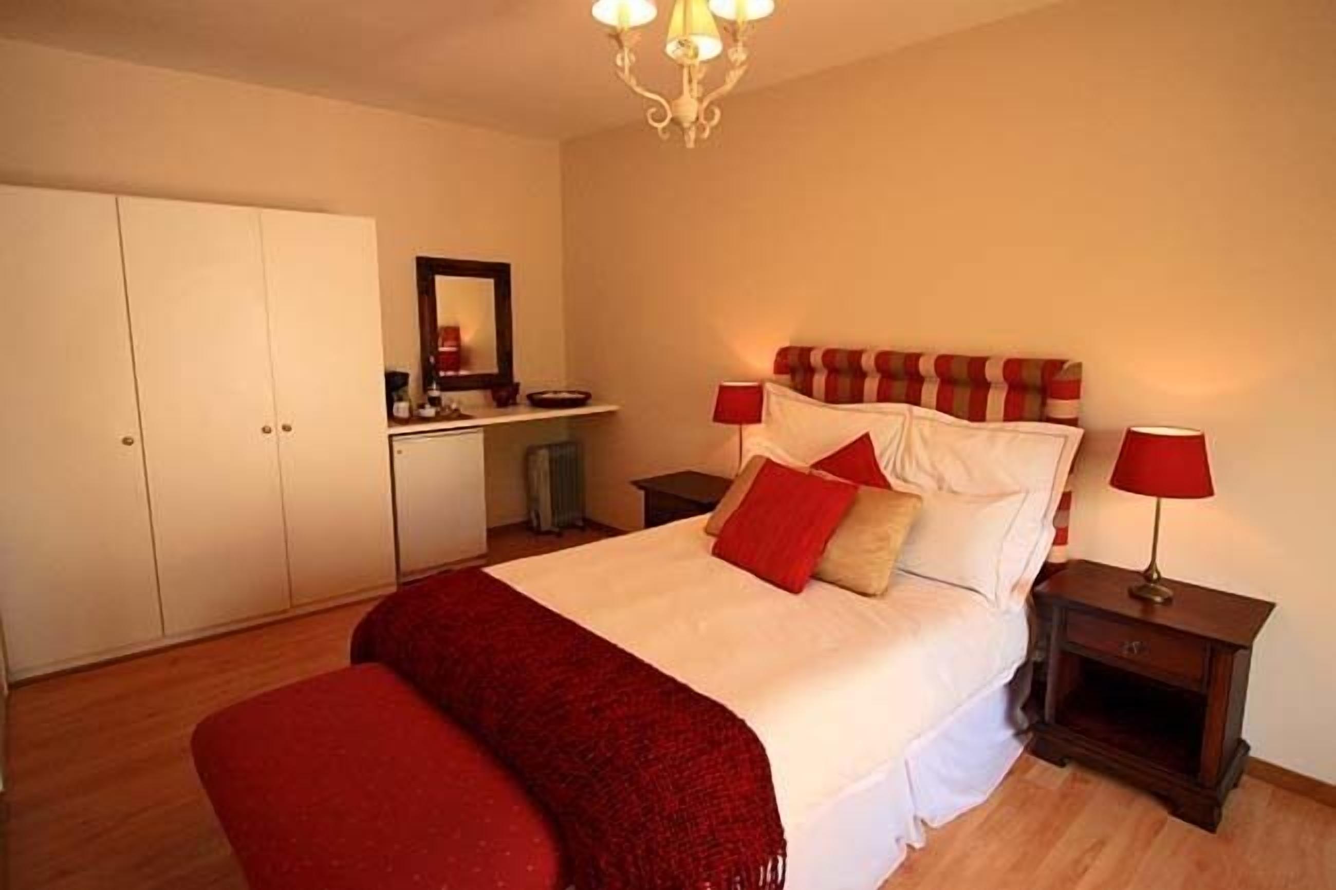 A bedroom with a bed, bedside tables, a wardrobe, and a mirror.