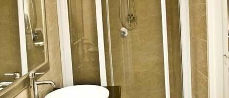 A bathroom with a white sink, a mirror, a shower enclosure, and a towel rack.