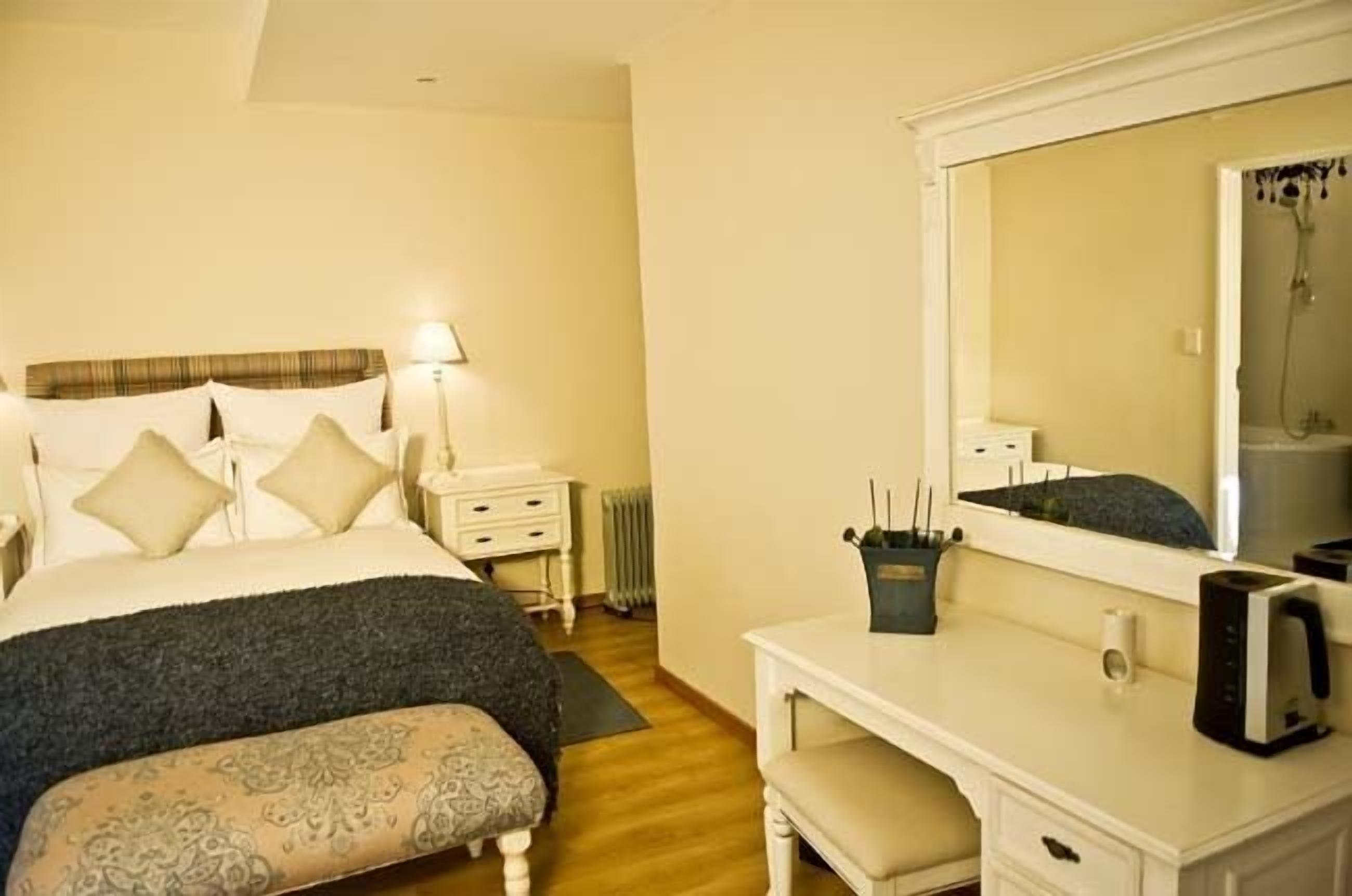 Une chambre à coucher avec un lit, une table de chevet, une lampe et un grand miroir.