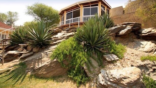 A house with a wooden exterior, large windows, and a balcony. - Villa Moringa Guesthouse (Windhoek)