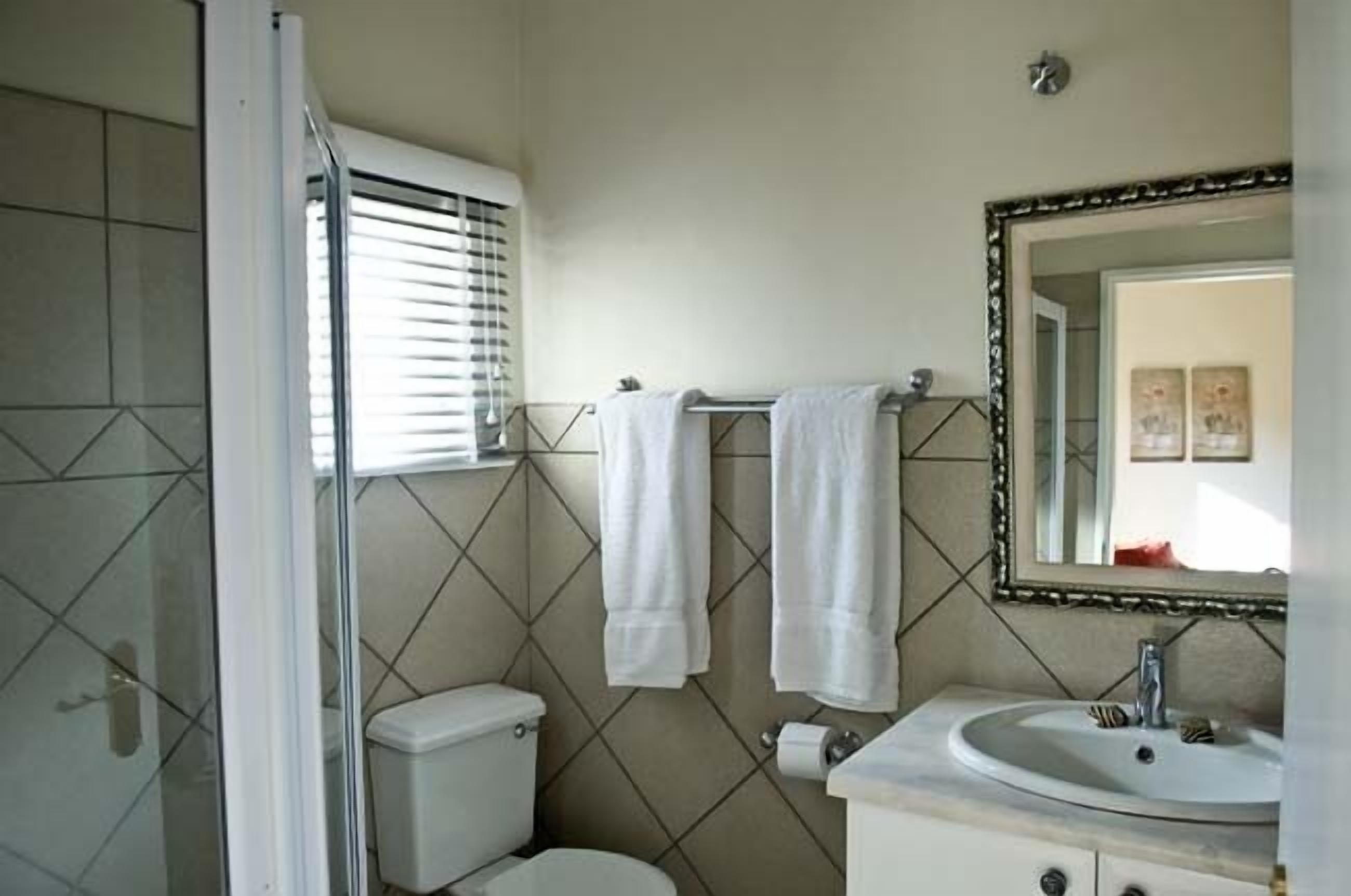 Een badkamer met toilet, wastafel en spiegel met decoratieve lijst.