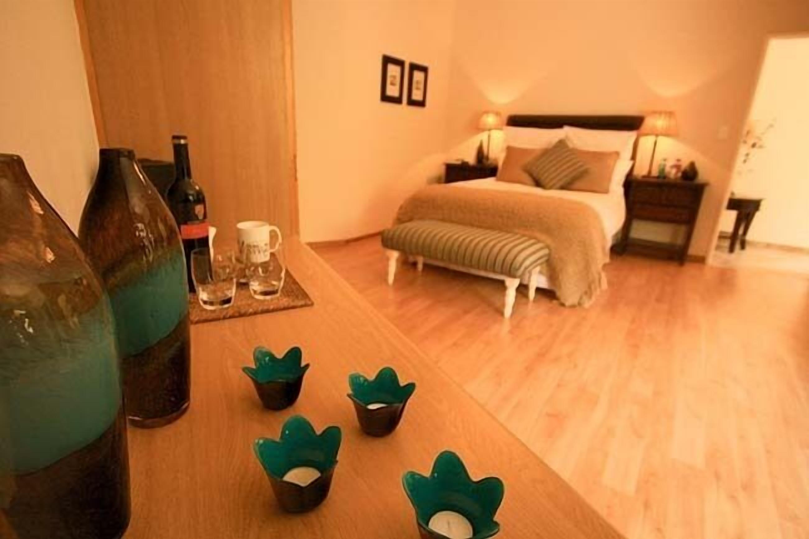 Una habitación de hotel con una cama, mesitas de noche y suelo de madera.