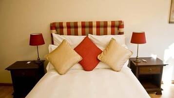 A neatly made bed with a striped headboard, two bedside tables with lamps, and a red pillow.