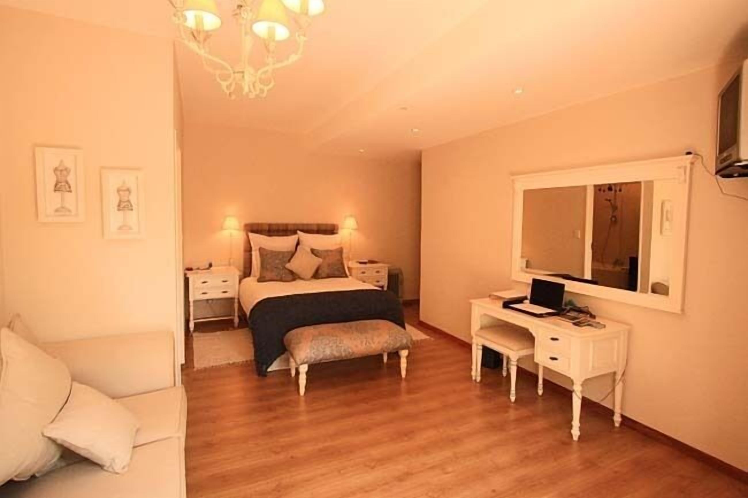 A bedroom with a bed, bedside tables, a desk, a chair, and a mirror.