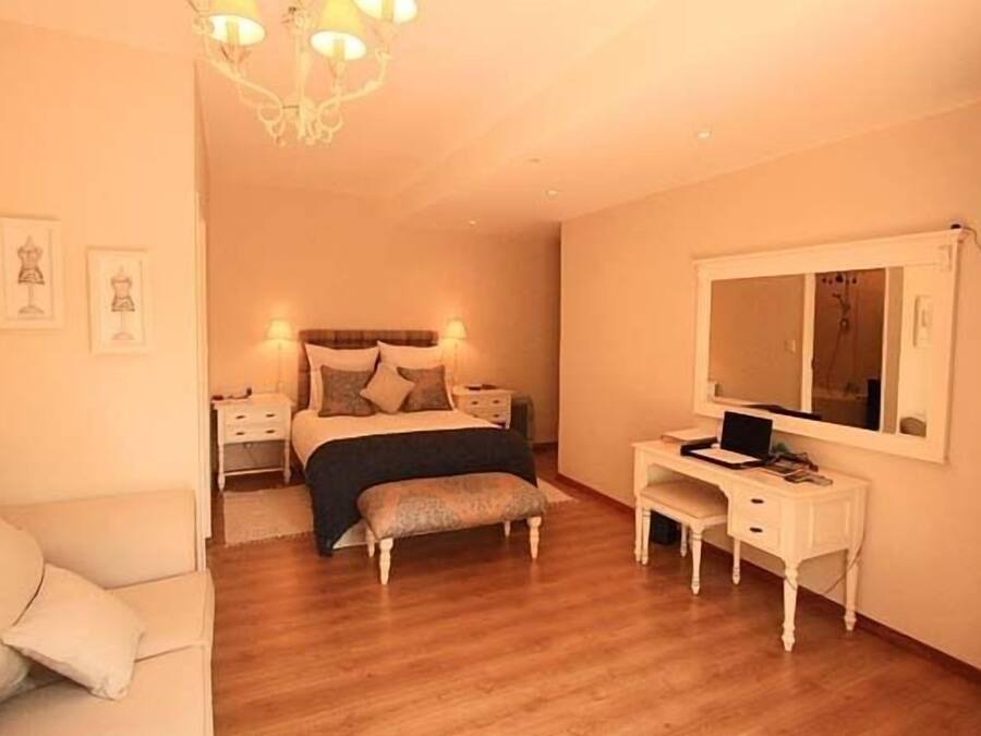 A bedroom with a bed, bedside tables, a desk, a chair, and a mirror.