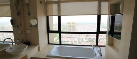 A modern bathroom with a large window, a bathtub, and a sink.