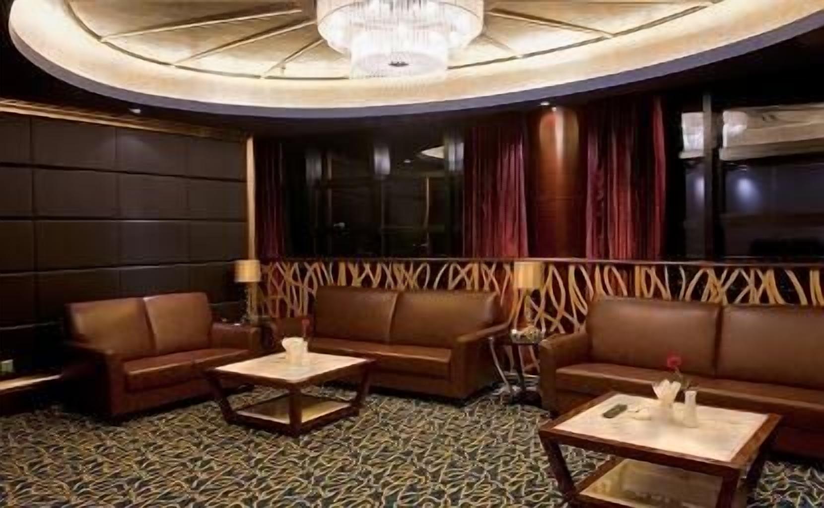 Eine luxuriöse Lounge mit Ledersofas, einem gemusterten Teppich und einer Kristallleuchter.