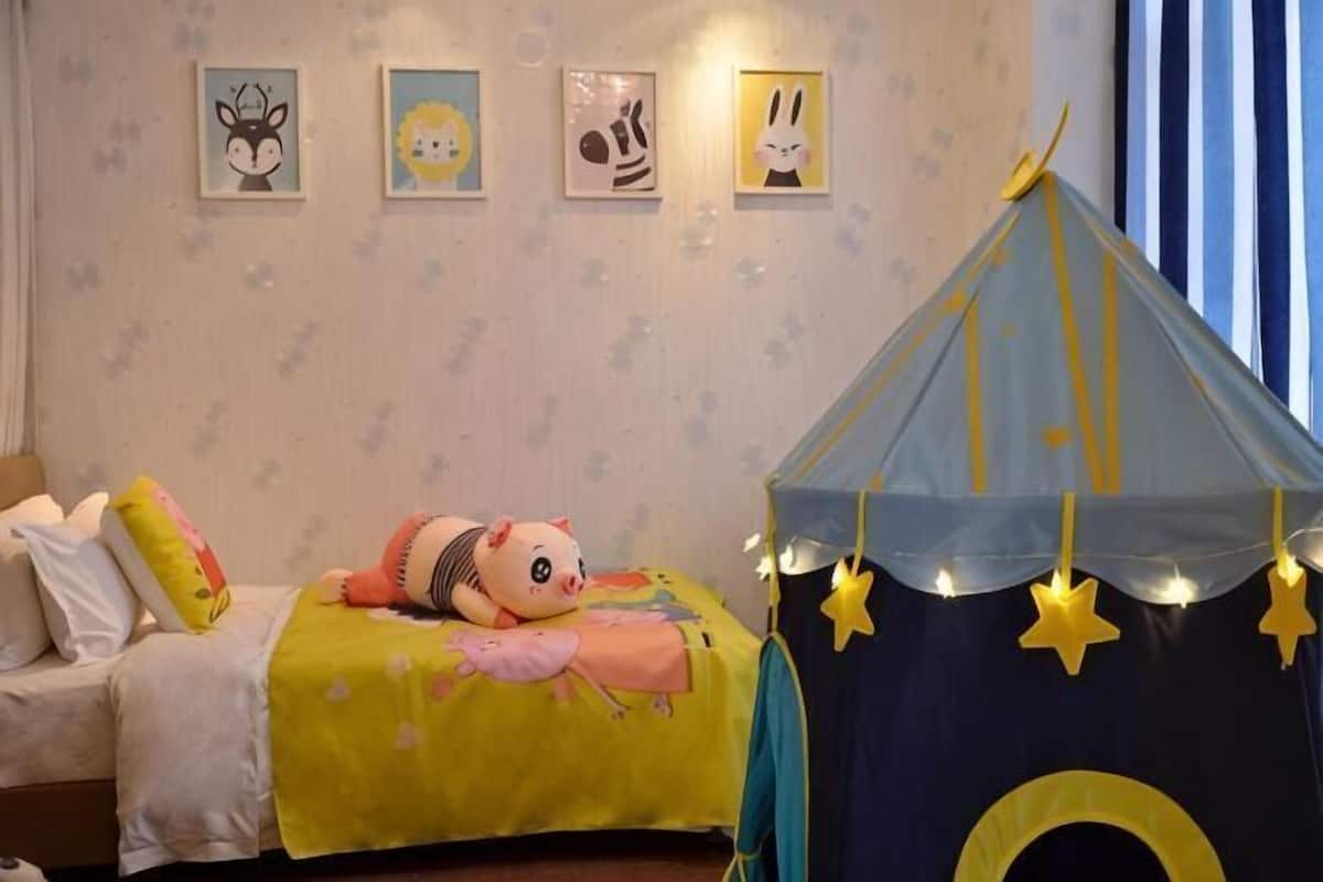 Un dormitorio infantil con una cama, una tienda de juegos y adornos en la pared.