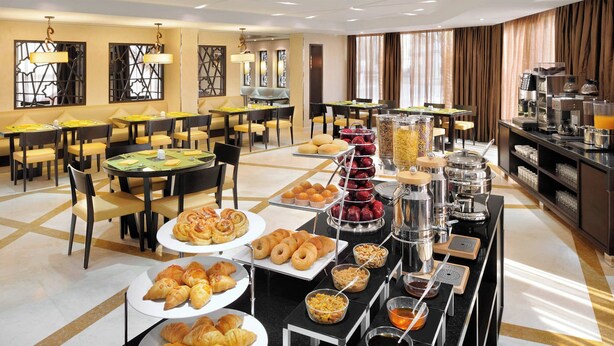 Um buffet de café da manhã com diversos pães, frutas e bebidas.