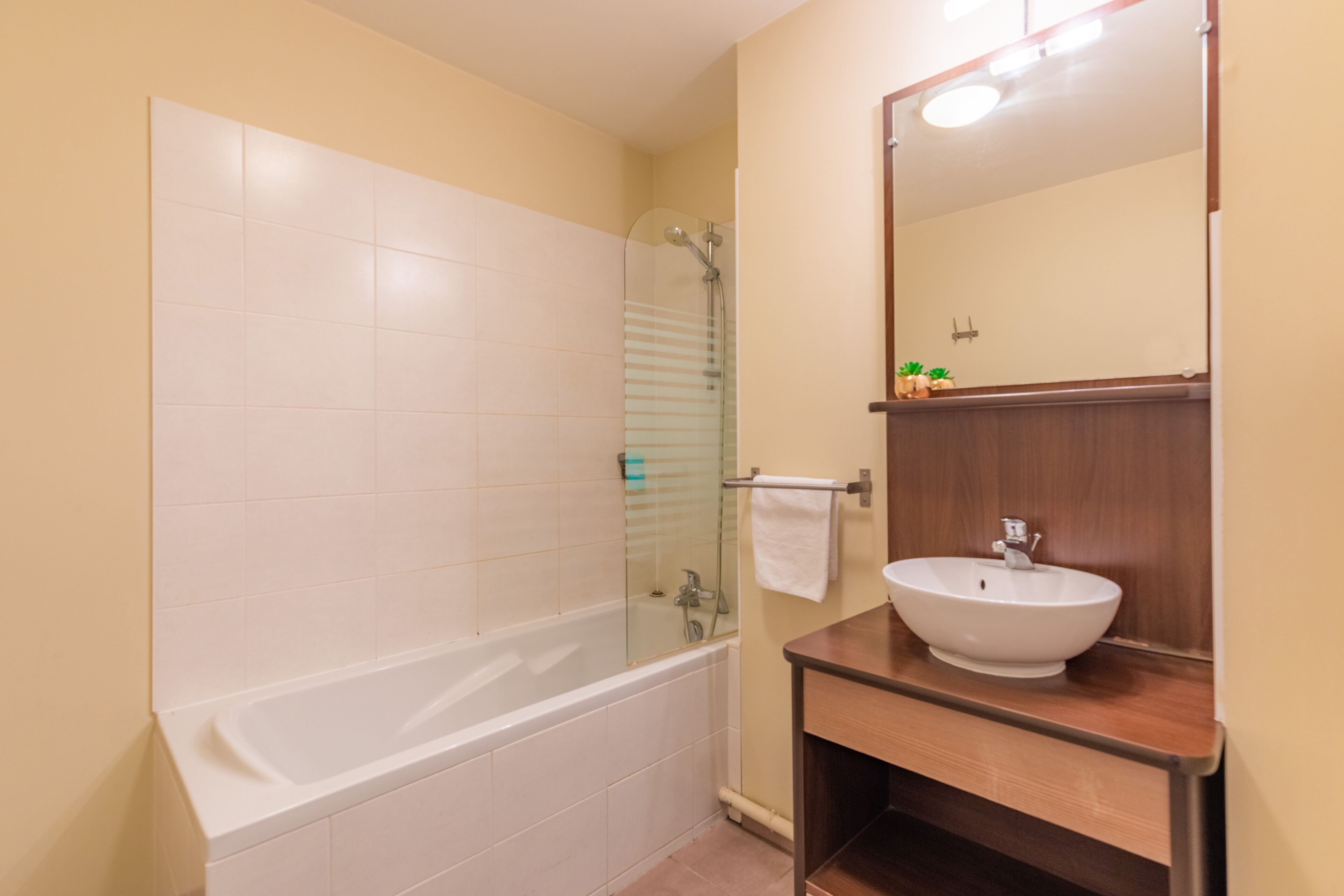 A bathroom with a bathtub, a glass-enclosed shower, and a wooden vanity with a sink.